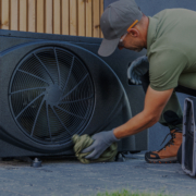 HVAC technician in British Columbia cleans an outdoor air conditioning unit, with a toolbox nearby for professional AC service.