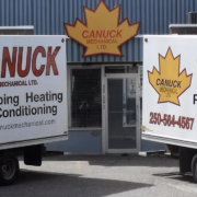 CANUCK Plumbing Heating Air Conditioning trucks with a maple leaf logo parked by the company’s blue BC HVAC service building.