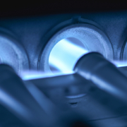 Close-up of blue flames in a gas furnace with three glowing burner tubes, highlighting efficient heating for British Columbia homes.