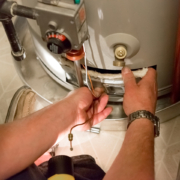 Technician repairing a water heater’s lower section with tools, insulation, and pipes visible—HVAC maintenance in British Columbia.