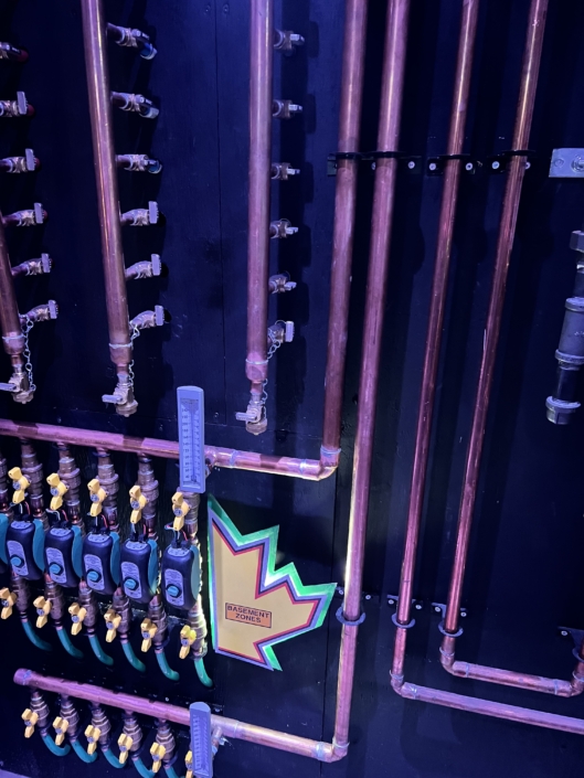 Organized copper pipes, valves, and meters on a wall with vibrant lighting—HVAC system installation in British Columbia.