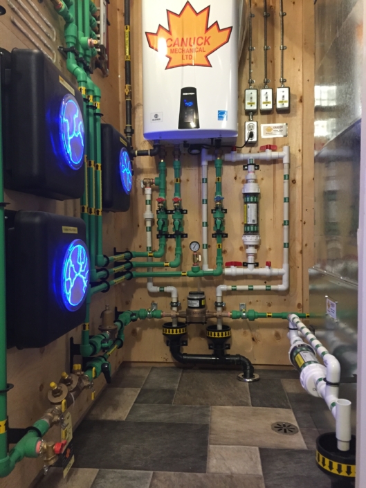Modern mechanical room in BC featuring green and white HVAC piping, Canuck Mechanical Ltd. water heater, control panels, and valves.